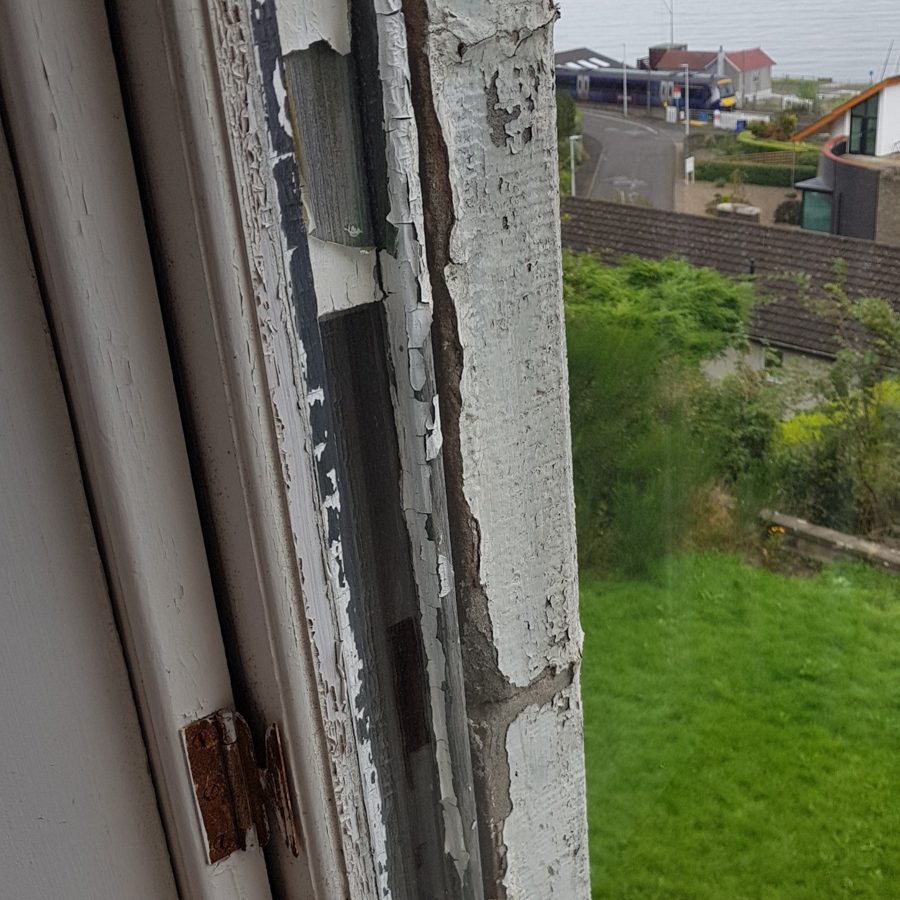 Cracked and flaking paint on a sash and its frame