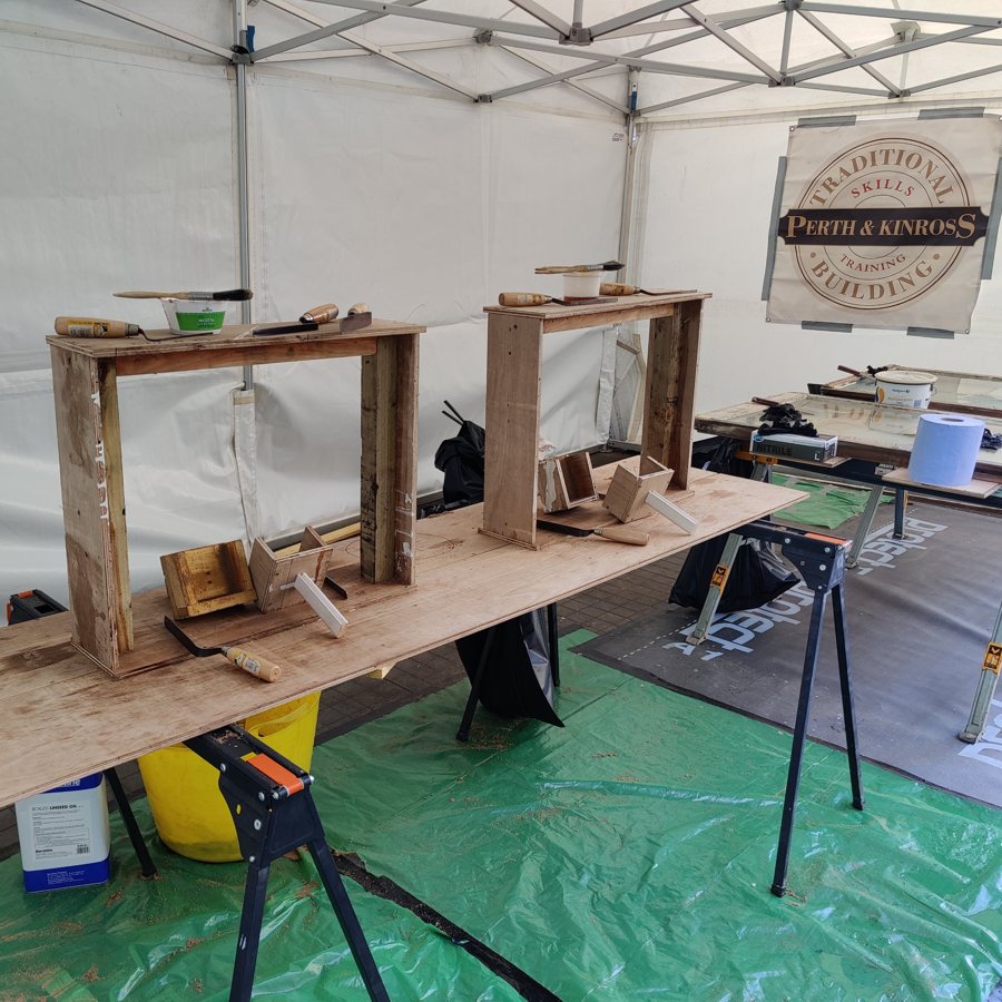 Traditional building skills training stand with practice window boxes, putty knives and linseed oil