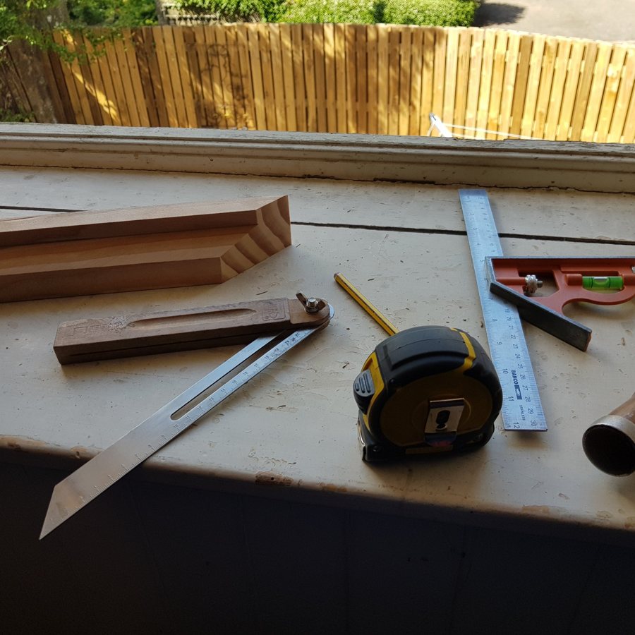 Sliding bevel, square, tape measure, chisel and a new timber moulding on a window board