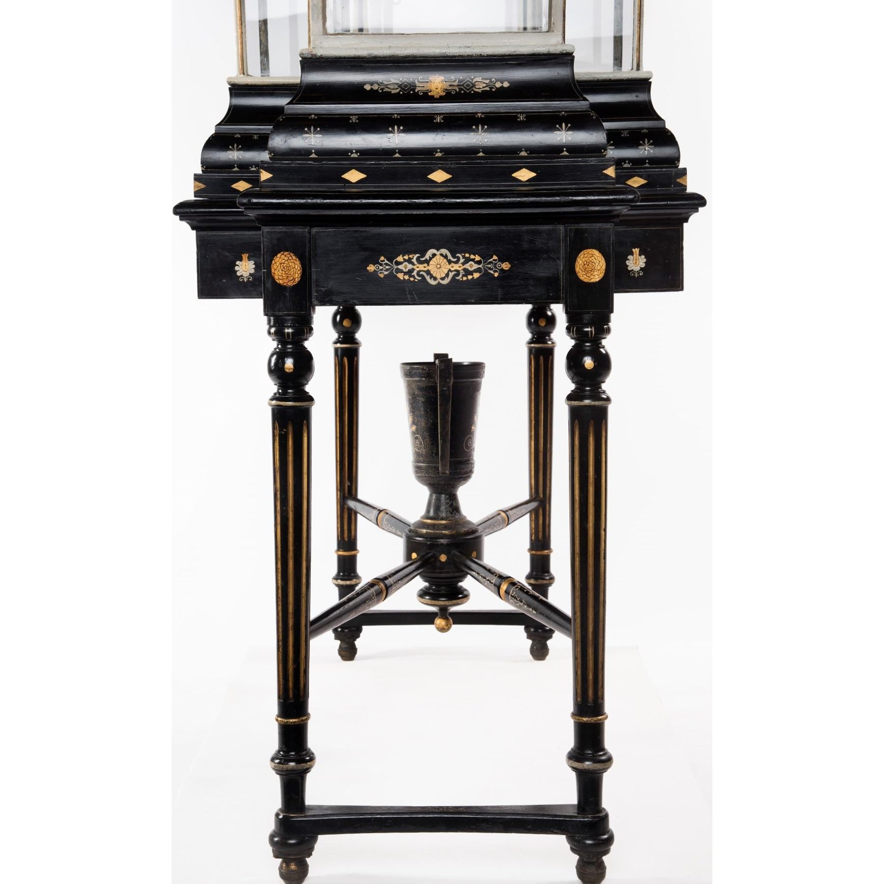 Side view of the ebonised stand with its fluted legs and the vase