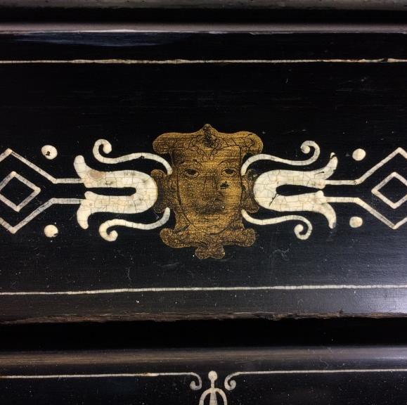 Gilded mask on the ebonised base, dulled by dirt